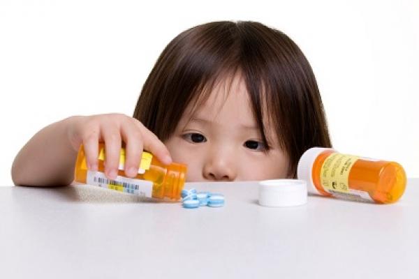 Child playing with spilled pill container on a table