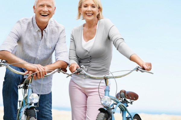 Old man and women riding bikes on a beach