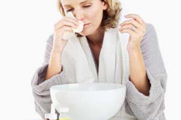 Women with a cold blowing her nose in a robe