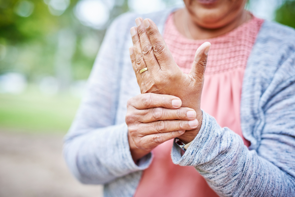 Older woman who seems to be suffering some pain while holding her hand close to her body